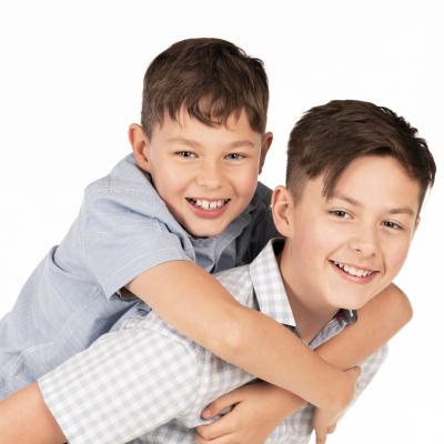 A boy giving a piggy back to his brother.