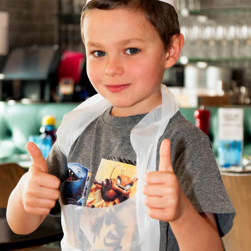 A boy in a paper hat and apron at a cooking party