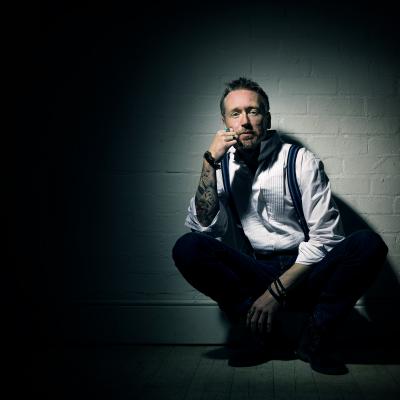 Ash Cooper in Moody lighting, crouched by a wall